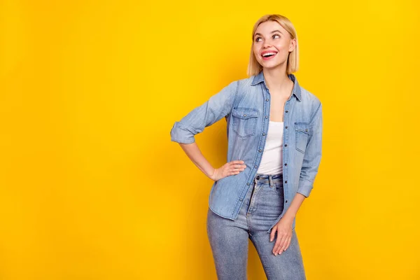 好奇心旺盛なブロンドの女の子の写真ポートレート笑顔身に着けているジーンズ服見てコピースペース隔離された鮮やかな黄色の背景 — ストック写真