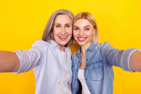 Mutlu anne ve kızın gülümseyen portresi selfie çekerken izole edilmiş sarı renkli arka plan. — Stok fotoğraf
