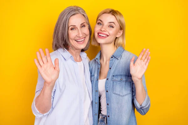 Foto portrét šťastné vnučky veselé babičky usmívající se mávání rukou pozdrav izolované živé žluté barvy pozadí — Stock fotografie