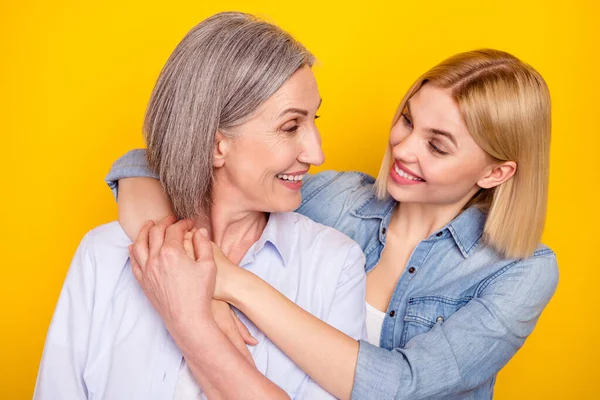 Фотопортрет матери и дочери, обнявших друг друга, держащих за руки изолированный ярко-желтый цвет фона — стоковое фото