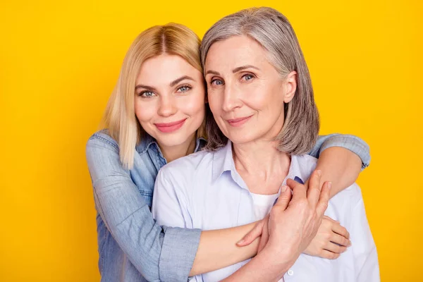 Retrato fotográfico de la hija abrazando a su madre sonriendo usando atuendo casual aislado color amarillo brillante fondo — Foto de Stock