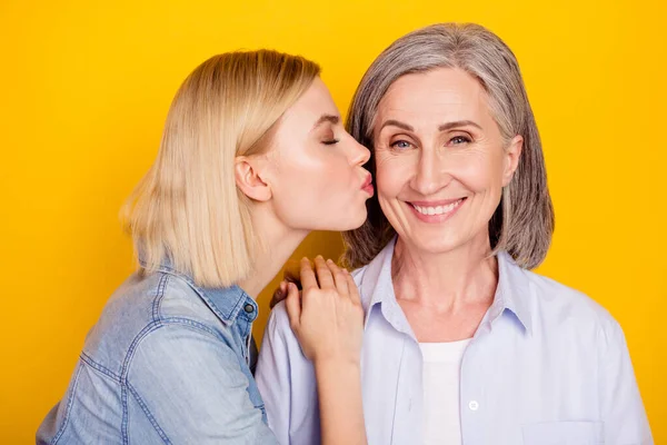 Foto retrato de la hija besando a su encantadora madre sonriendo aislado color amarillo brillante fondo — Foto de Stock