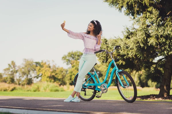 Foto de corpo inteiro de morena pele escura mulher feliz fazer selfie no parque de bicicleta fazer v-sign no campo fora ao ar livre — Fotografia de Stock