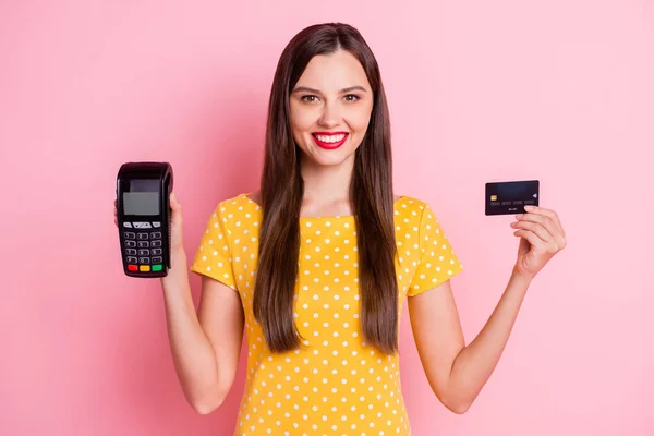 Foto av vackra bruna hår flicka bära gul polka dot t-shirt hålla terminal kreditkort isolerad på rosa färg bakgrund — Stockfoto