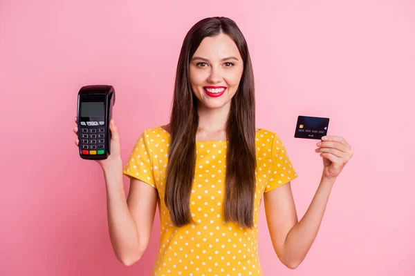 Foto av ganska brun hår flicka bära gul prickig t-shirt hålla kreditkort terminal isolerad på pastell rosa färg bakgrund — Stockfoto