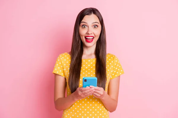 令人惊讶的女人拿着电话惊奇的通知穿着黄色点缀的T恤在粉色背景下被隔离销售的照片 — 图库照片