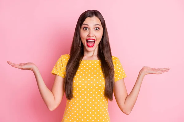 Foto de mujer joven feliz asombrada usar amarillo punteado camiseta tomados de la mano espacio vacío aislado en el fondo de color rosa — Foto de Stock