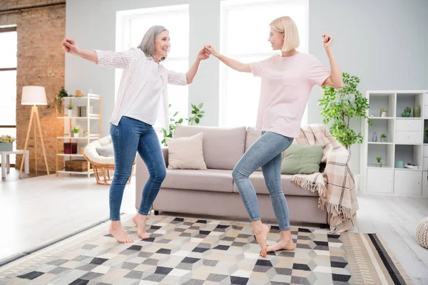 Full body profile side photo of funky mom and daughter smile dance hold hands indoors inside house home — Stock fotografie