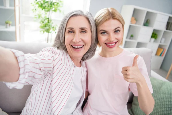 Foto von grauhaarigen blonden glücklichen Frauen Familie sitzen Couch Selfie zeigen Daumen nach oben drinnen im Haus — Stockfoto