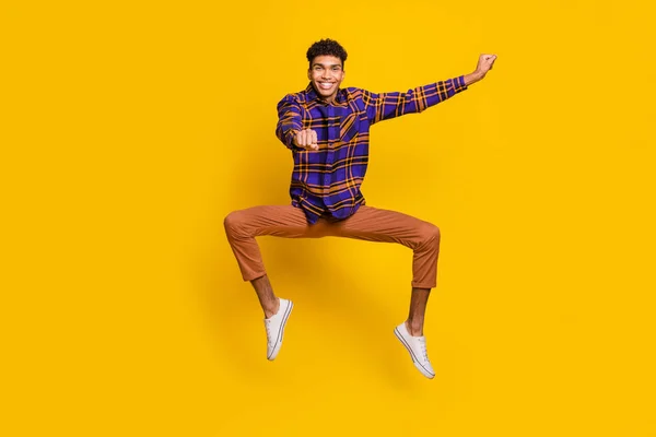 Foto de longitud completa de despreocupado guapo hombre de piel oscura salto paseo imaginar caballo aislado sobre fondo de color amarillo — Foto de Stock