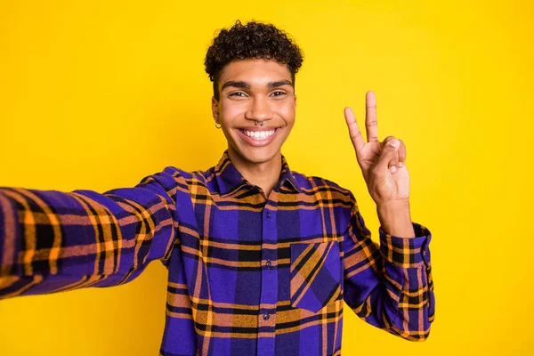 Foto ritratto di giovane uomo sorridente allegro felice mostrando v-segno due dita prendendo selfie isolato luminoso colore giallo sfondo — Foto Stock