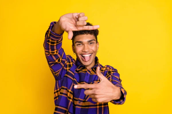Foto de jovem afro alegre homem sorriso feliz grimace tongue-out fazer dedos quadro instantâneo isolado sobre fundo de cor amarela — Fotografia de Stock
