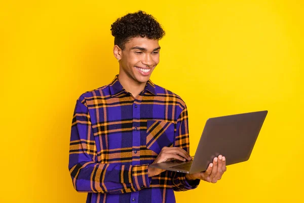 Foto portrét mladého muže pracující na notebooku s úsměvem izolované jasně žluté barvy pozadí — Stock fotografie