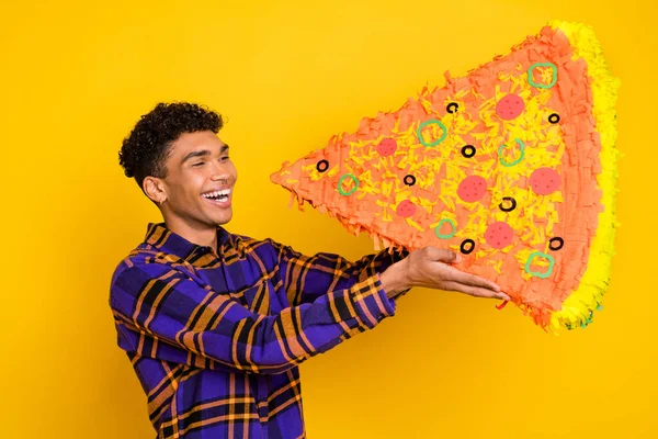 Foto de perfil lateral del joven negro feliz sonrisa comer rebanada grande sabrosa pizza italiana aislada sobre fondo de color amarillo —  Fotos de Stock