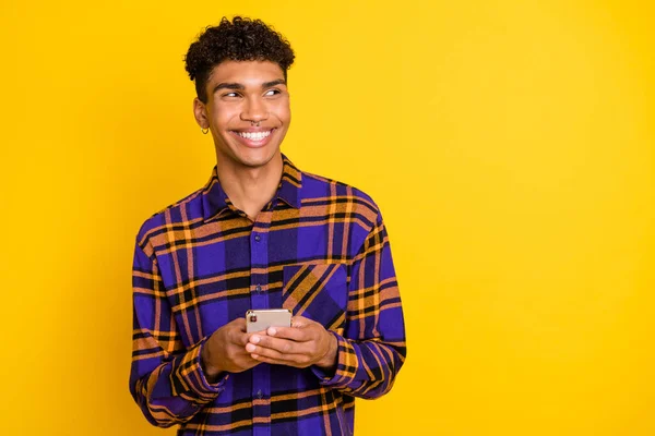Foto ritratto di uomo navigazione internet cellulare cercando spazio vuoto indossare vestito a scacchi isolato su vivido sfondo di colore giallo — Foto Stock