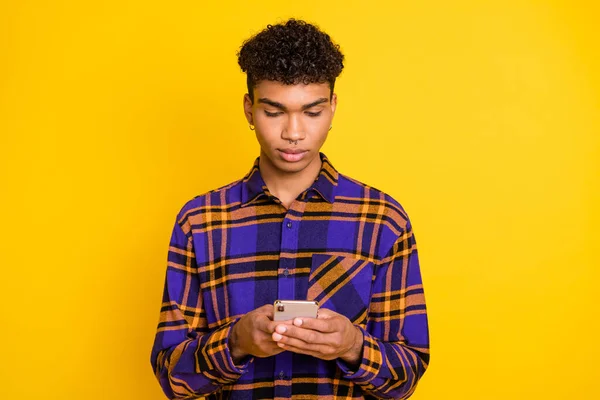 Foto portret van de mens typen bericht op mobiele telefoon dragen geruite shirt geïsoleerd op levendige gele kleur achtergrond — Stockfoto