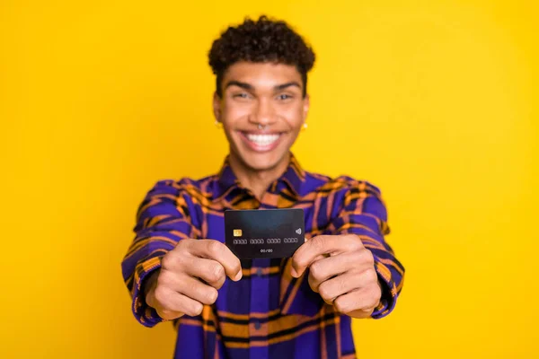Foto de piel oscura satisfecha que sostienen las manos demuestran tarjeta de débito aislada sobre fondo de color amarillo — Foto de Stock