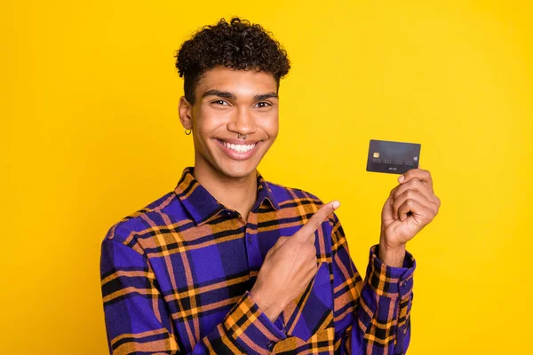 Foto retrato de un tipo señalando el dedo en la tarjeta de crédito de plástico aislado en el fondo de color amarillo brillante — Foto de Stock