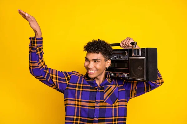 Foto ritratto di bel ragazzo sorridente mantenendo registratore retrò cercando spazio vuoto danza isolato su vibrante sfondo di colore giallo — Foto Stock