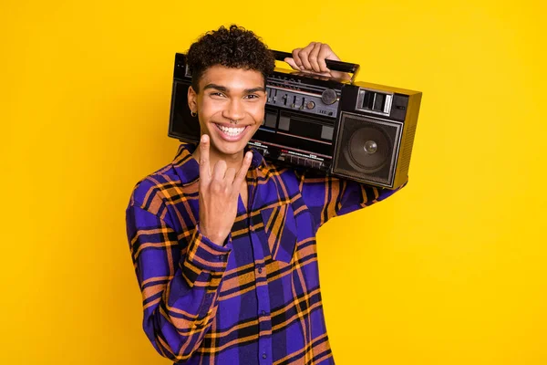 Photo of young black man happy positive smile hold boombox show fingers rock sign isolated over yellow color background — Stock Photo, Image