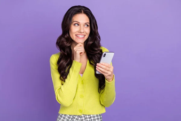 Foto-Porträt der brünetten Frau suchen leeren Raum berühren Kinn hält Handy isoliert auf pastellvioletten Hintergrund — Stockfoto