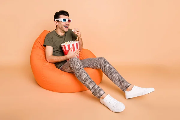 Photo de gars assis haricot tenir boîte pop-corn regarder vide espace porter 3d lunettes vert t-shirt isolé beige couleur fond — Photo