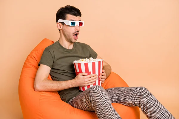 Foto retrato de homem sentado na cadeira assistindo tv comer milho pop usando óculos 3d isolado no fundo cor bege pastel — Fotografia de Stock