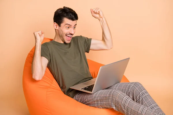 Φωτογραφία του hooray brunet guy sit look laptop wear t-shirt παντελόνι απομονώνονται σε μπεζ χρώμα φόντο — Φωτογραφία Αρχείου