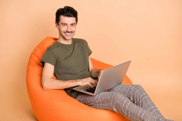 Photo de jeune homme d'affaires souriant de bonne humeur assis chaise travaillant sur ordinateur portable isolé sur fond de couleur beige — Photo