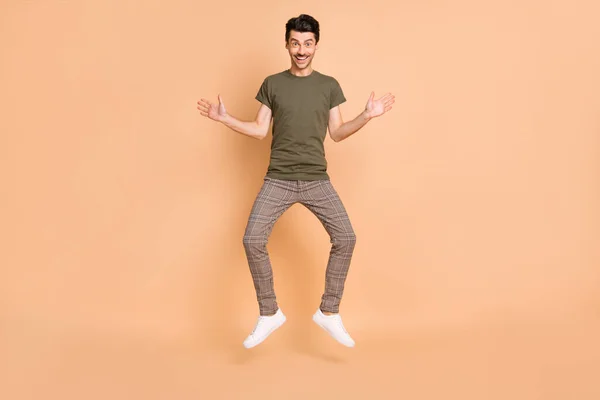 Full length body size photo of jumping funny man smiling wearing casual clothes isolated on pastel beżowy kolor tła — Zdjęcie stockowe