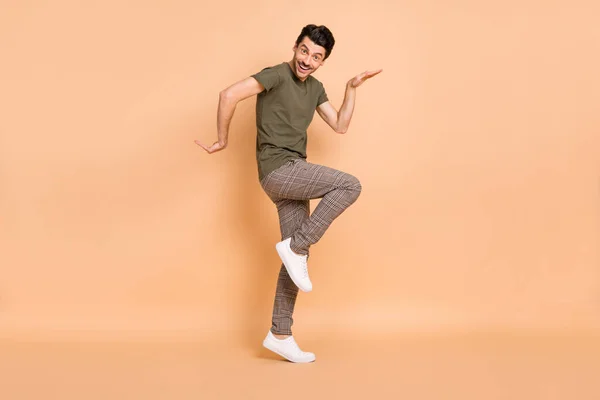 Foto de perfil de tamaño completo de hooray morena chico danza desgaste camiseta pantalones zapatillas aisladas sobre fondo de color beige — Foto de Stock