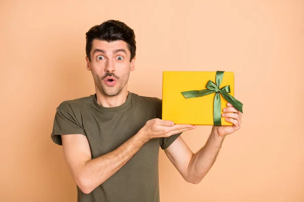 Foto de joven sorprendido sorprendido hombre sorprendido mostrando demostrando presente inesperado aislado sobre fondo de color beige —  Fotos de Stock