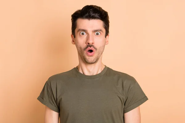 Foto retrato del hombre asombrado mirando con la boca abierta usando camiseta verde aislada sobre fondo de color beige pastel — Foto de Stock