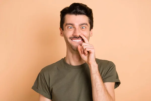 파스텔 베이지 컬러 배경에 고립된 바보같은 코미디언의 코에 손가락을 넣는 남자 사진 — 스톡 사진
