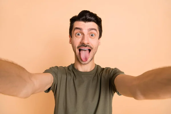 Foto van jonge funky grappig glimlachen positieve kinderachtige man tonen tong nemen selfie geïsoleerd op pastel kleur achtergrond — Stockfoto