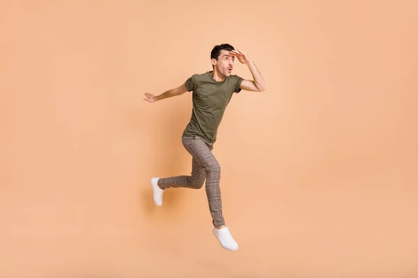 Full längd kropp storlek foto av hoppa hög man ser fram emot långt hand nära pannan isolerad på pastell beige färg bakgrund — Stockfoto