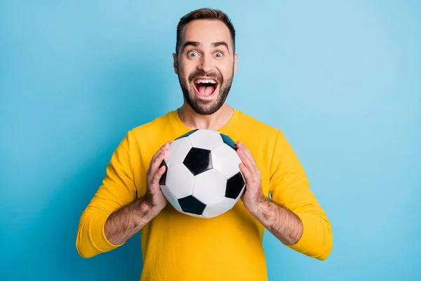 Фото молодых взволнованных сумасшедших счастливый позитивный улыбающийся веселый человек держать футбольный мяч в руках изолированы на синем фоне цвета — стоковое фото