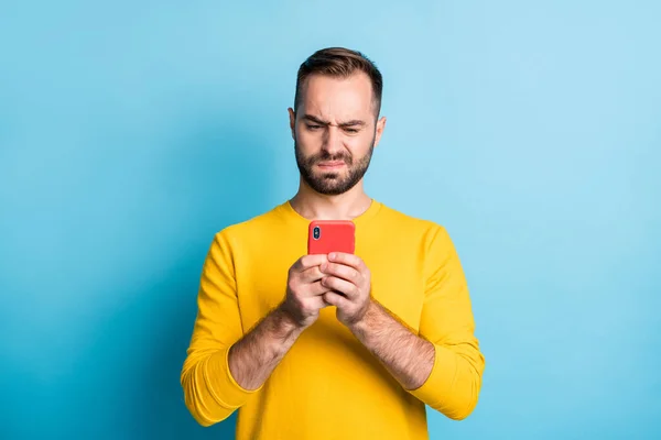 Photo of young unhappy upset sad unsure uncertain man see dislike bad comment in phone isolated on yellow color background — 图库照片