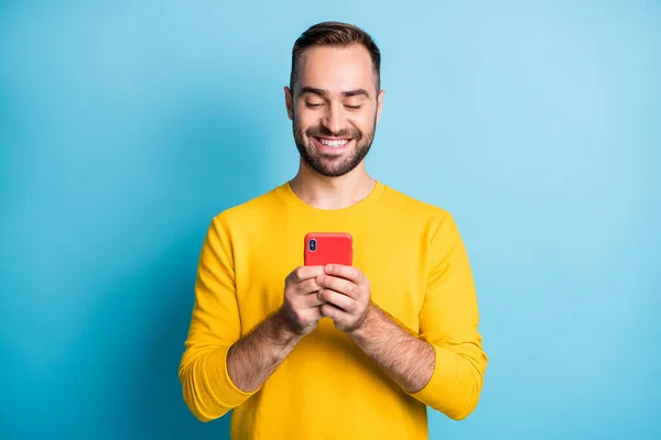 Photo portrait of happy man wearing yellow outfit browsing internet on cellphone smiling isolated on vibrant blue color background — 图库照片