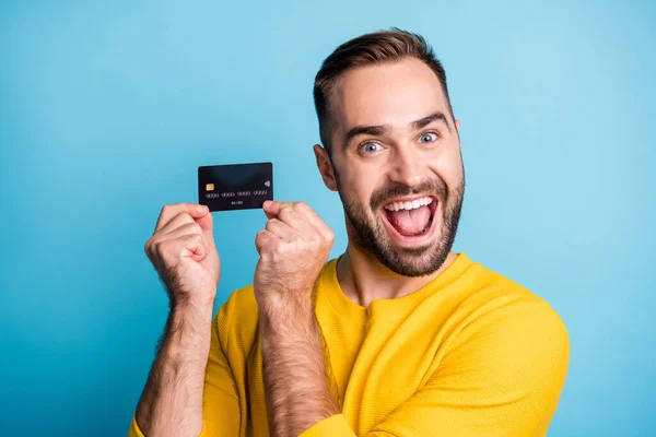 파란 배경에 고립된 신용 카드를 보여 주고 있는 젊고 잘생긴 젊은 잘생긴 미친 웃음을 짓고 있는 젊은 남자의 사진 — 스톡 사진