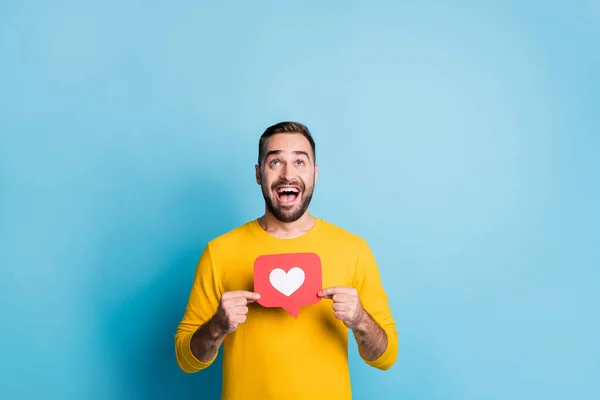 Foto de jovem feliz animado bom humor sorridente homem segurar ícone do coração olhar copyspace isolado no fundo de cor azul — Fotografia de Stock