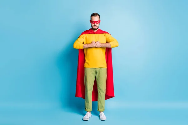 Foto em tamanho completo de jovem bonito sério super homem poderoso em capa vermelha e máscara isolada no fundo de cor azul — Fotografia de Stock