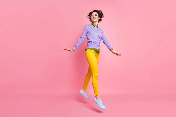 Full size photo of cheerful lady jump up good mood wear jumper yellow pants sneakers isolated pink color background — 图库照片