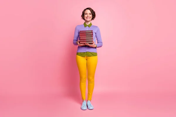 Πλήρης φωτογραφία του γοητευτικού μαθητή κυρία μεταφέρουν πολλά βιβλιοθήκη βιβλίο φορούν πουλόβερ παντελόνι παπούτσια απομονωμένο ροζ χρώμα φόντο — Φωτογραφία Αρχείου