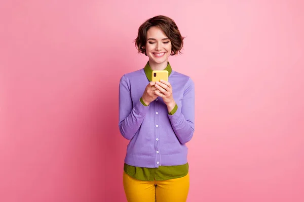 Foto de señora divertida sostener teléfono manos usar púrpura jersey pantalones amarillos aislados de color rosa fondo — Foto de Stock