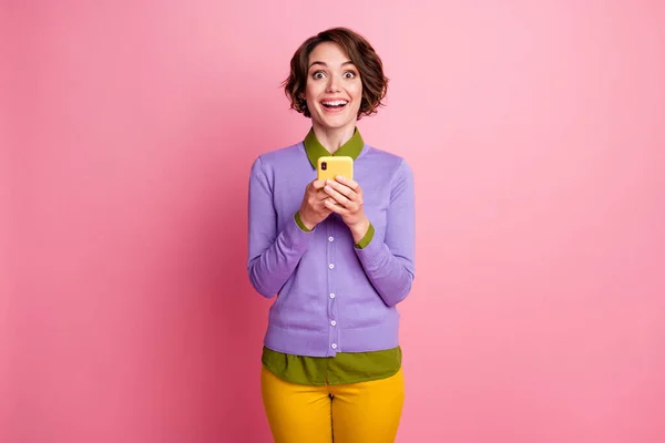 Foto de señora divertida mantener el teléfono chateando amigos usan pantalones de jersey púrpura aislado color rosa fondo —  Fotos de Stock