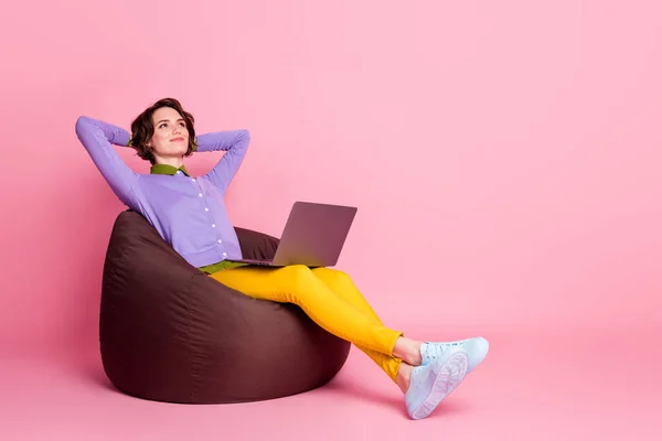 Full size profiel zijkant foto van kalm meisje zitten boon stoel werk laptop ontspannen dragen broek shirt geïsoleerde pastel kleur achtergrond — Stockfoto