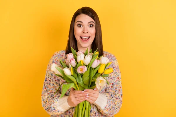 Foto de encantadora mujer feliz agradable sorprendida sostener flores tulipanes sorpresa aislado sobre fondo de color amarillo brillante — Foto de Stock