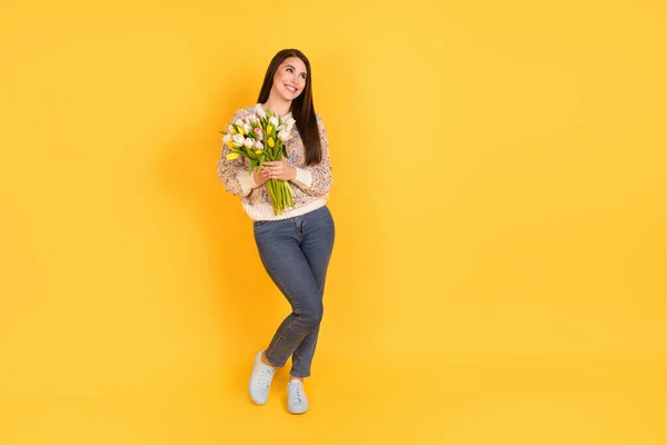 밝고 명랑 한 여성의 전신 사진빈 공간을 잡고 손을 잡고 노란 색 배경에 고립된 꽃을 보고 있다 — 스톡 사진