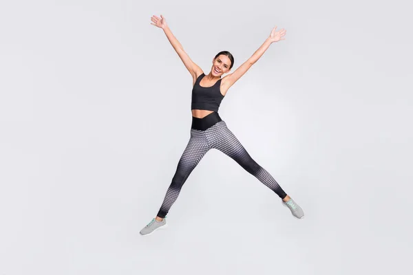 Foto de longitud completa de encantadora mujer joven alegre saltar forma de estrella deportiva aislado sobre fondo de color gris —  Fotos de Stock